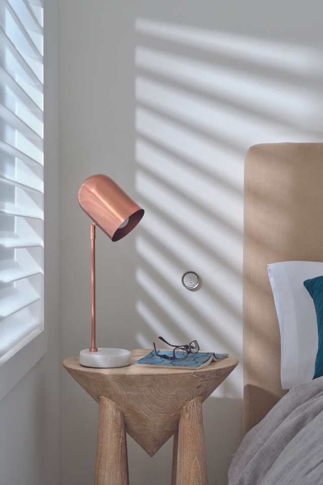 white automated blinds in modern minimal bedroom with copper bedside lamp
